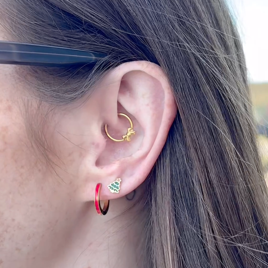 Close-up of an ear with multiple earrings against a blurred background