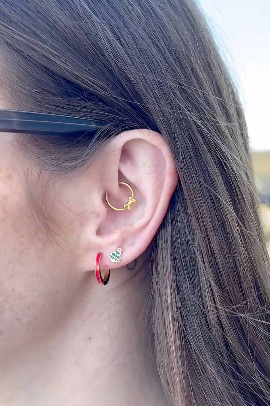 Close-up of an ear with multiple earrings against a blurred background