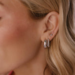 Close-up of a person wearing silver hoop earrings with a blurred background