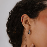 Close-up of an ear with a hoop earring against a neutral background