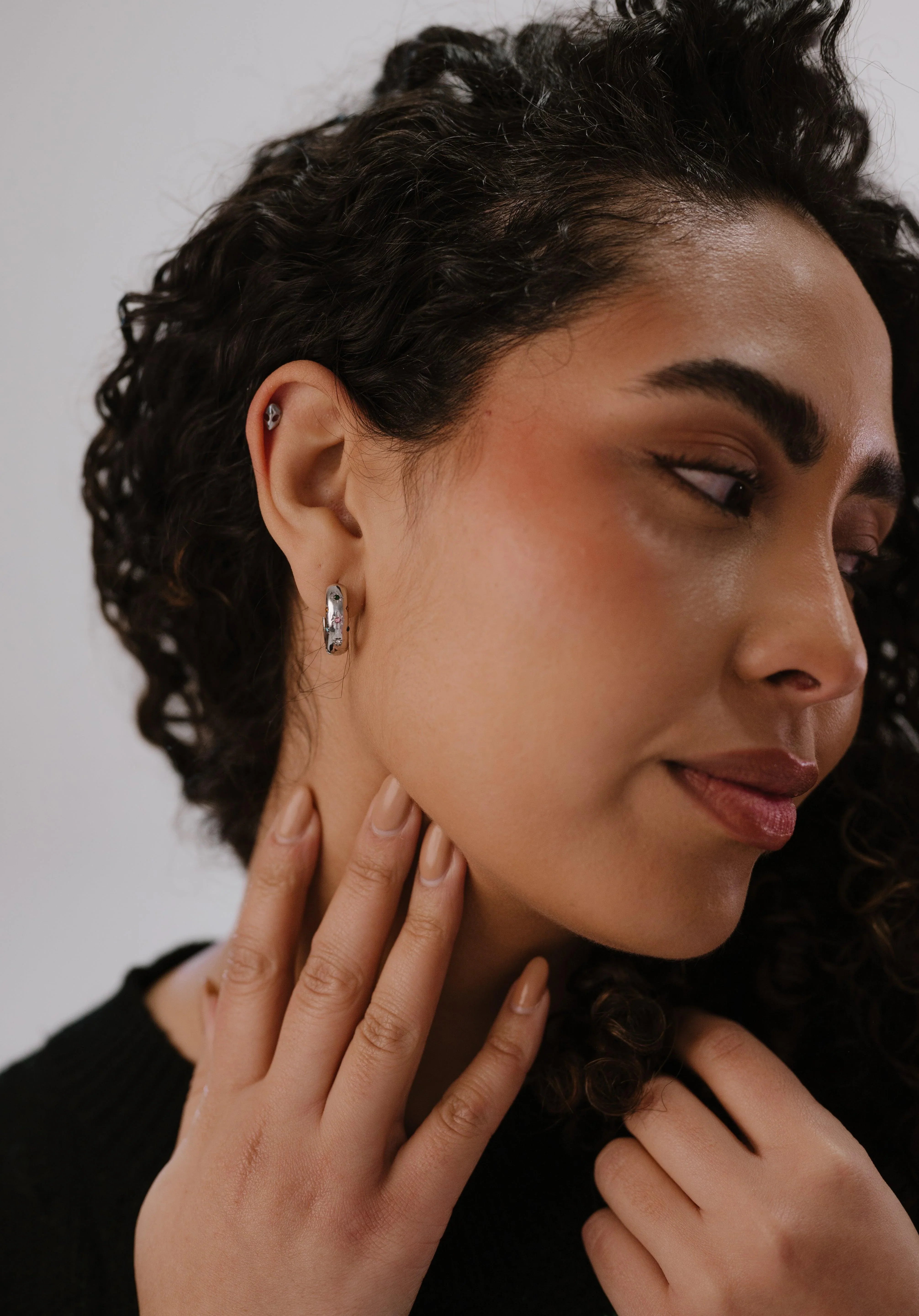 Woman wearing a diamond earring with a neutral background