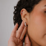Close-up of a person wearing earrings with a neutral background