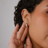 Close-up of a person wearing earrings with a neutral background
