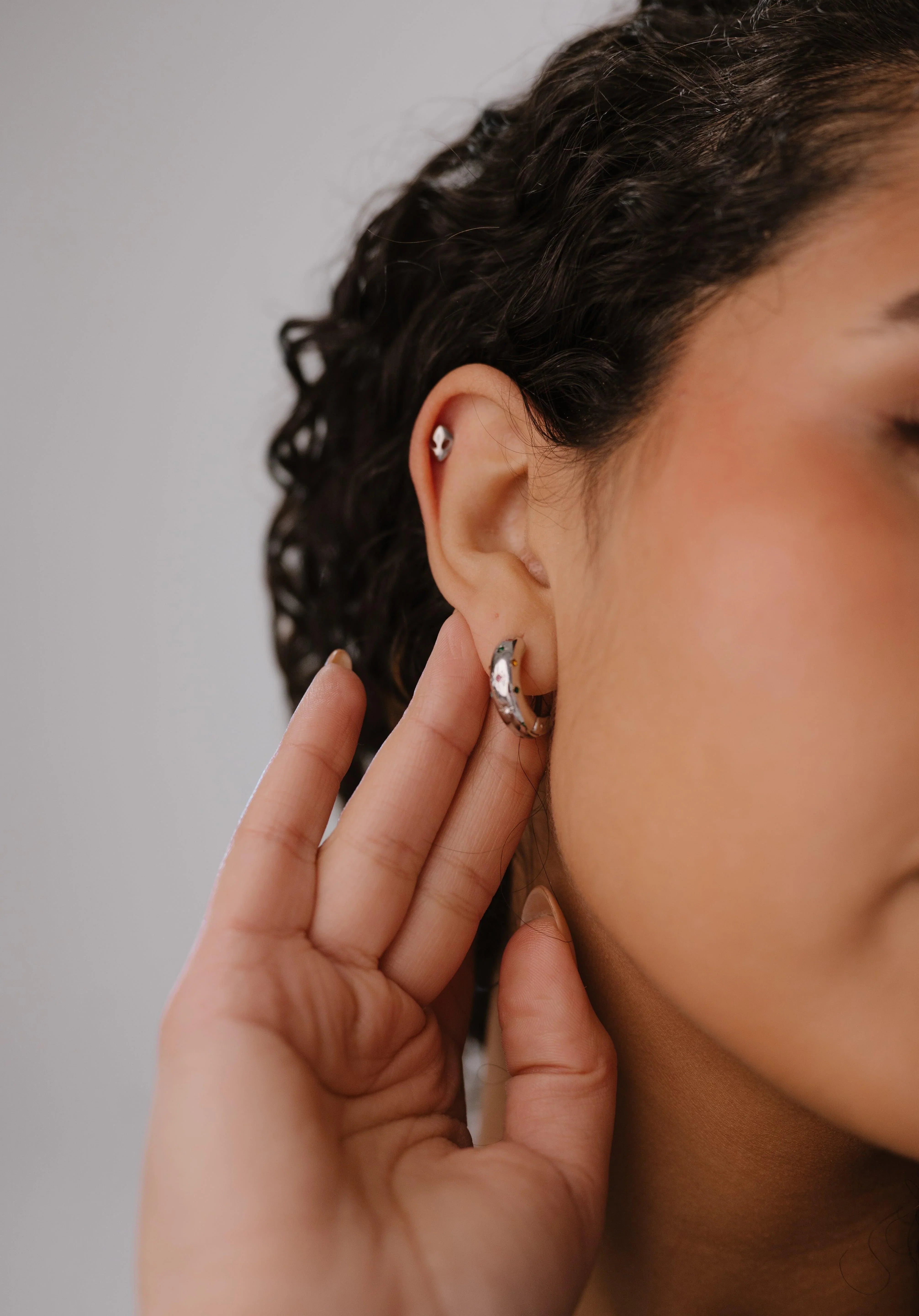 Close-up of a person wearing earrings with a neutral background