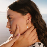 Woman wearing gold earrings with a blurred background