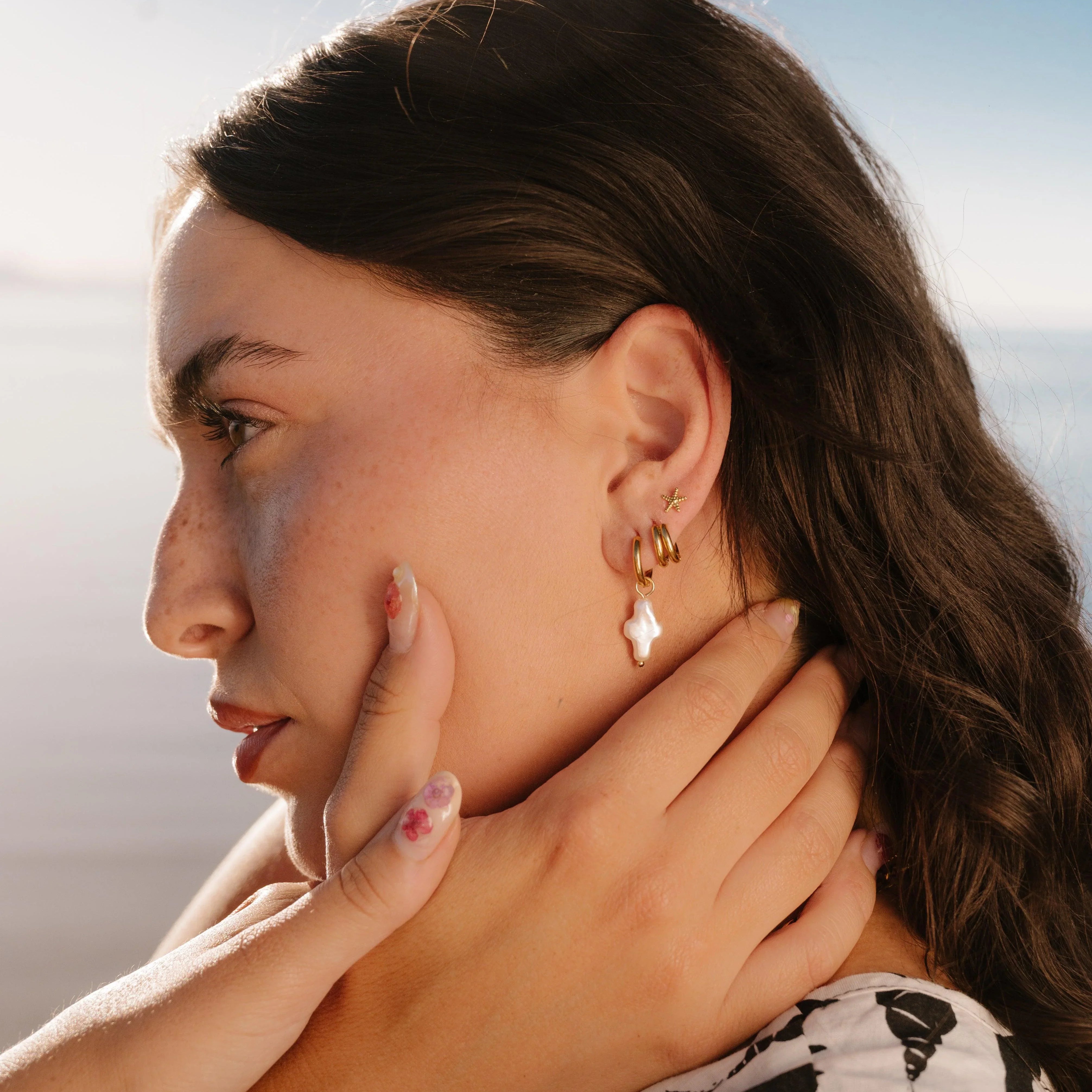 Woman wearing gold earrings with a blurred background
