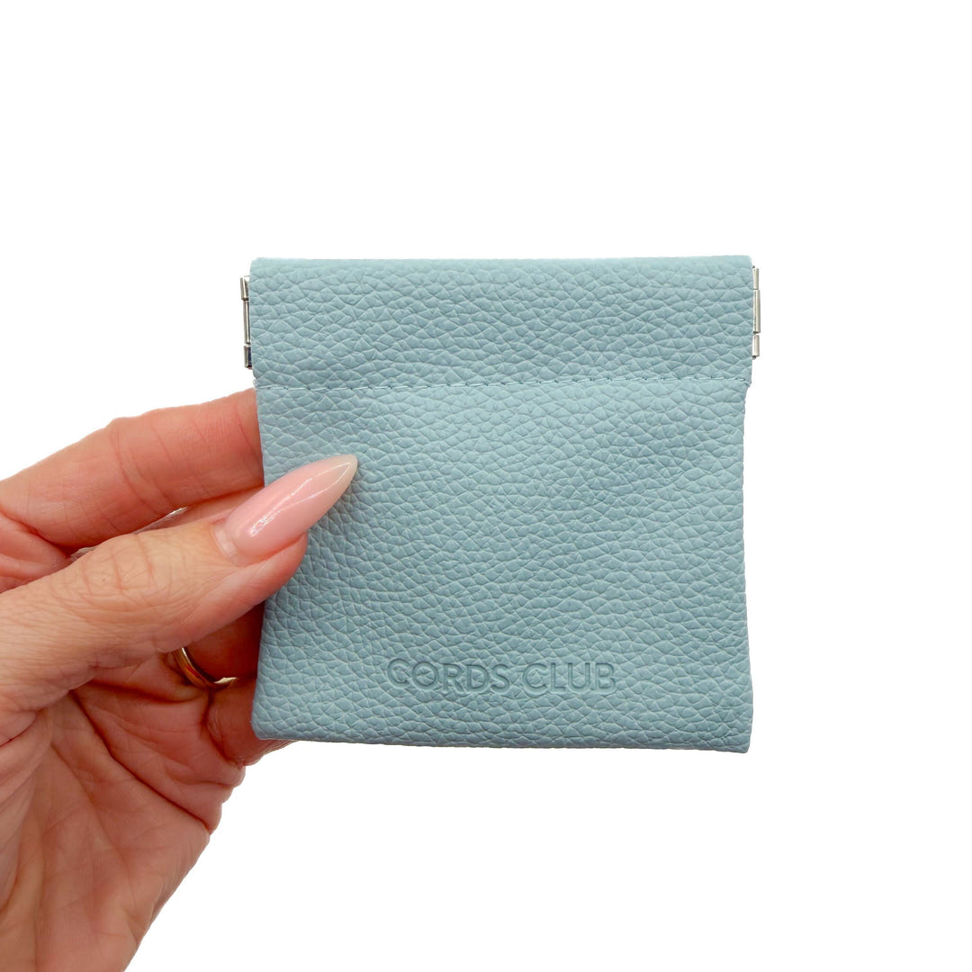 Light blue faux leather closeable pouch held by a hand on a white background