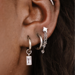 Close-up of an ear with multiple silver hoop earrings.