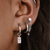 Close-up of an ear with multiple silver hoop earrings.
