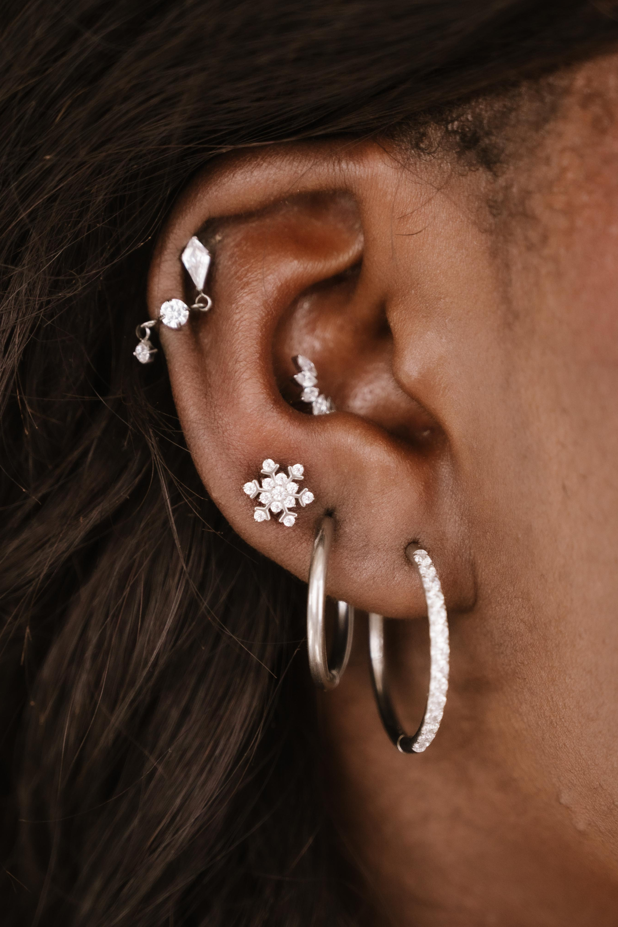 Close-up of an ear with multiple silver and clear zirconia earrings