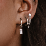 Close-up of an ear with multiple silver hoop earrings.