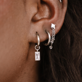 Close-up of an ear with multiple silver hoop earrings.