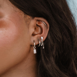 Close-up of an ear with multiple earrings against a blurred background