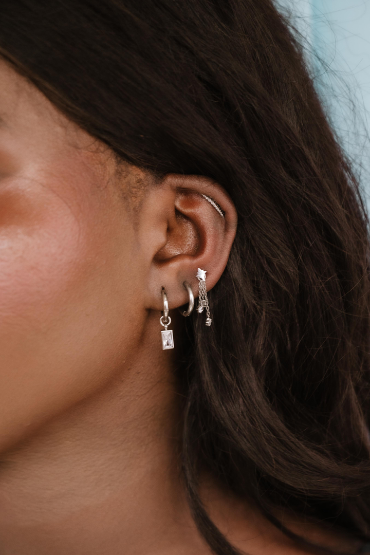 Close-up of an ear with multiple earrings against a blurred background
