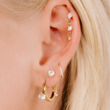 Close-up of an ear with multiple gold and diamond earrings against a blurred background