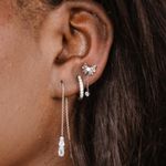 Close-up of an ear with silver earrings against a dark background