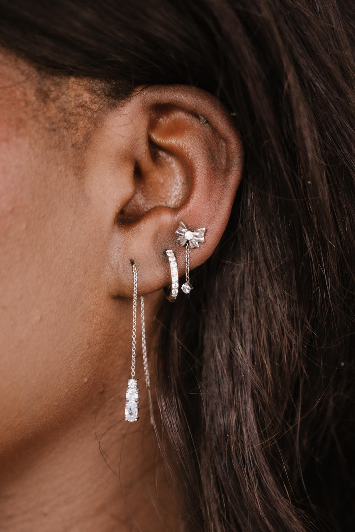 Close-up of an ear with silver earrings against a dark background