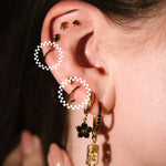 Close-up of an ear with gold earrings and a hand adjusting them.