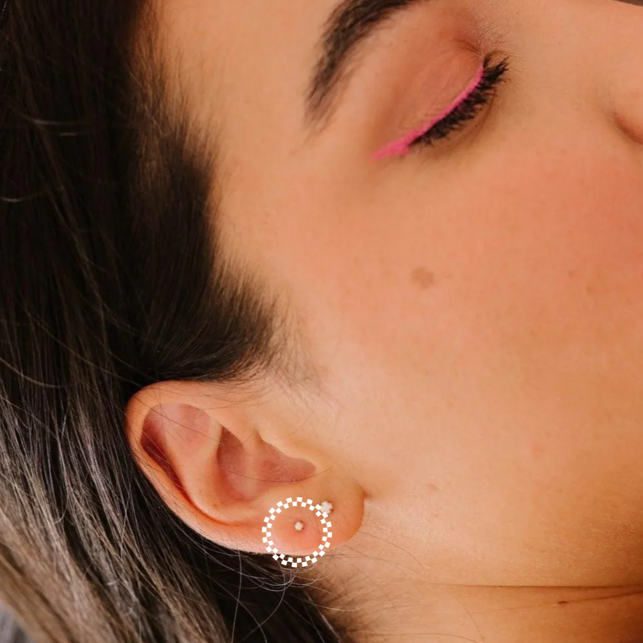 Close-up of a woman wearing a circular earring with a blurred background