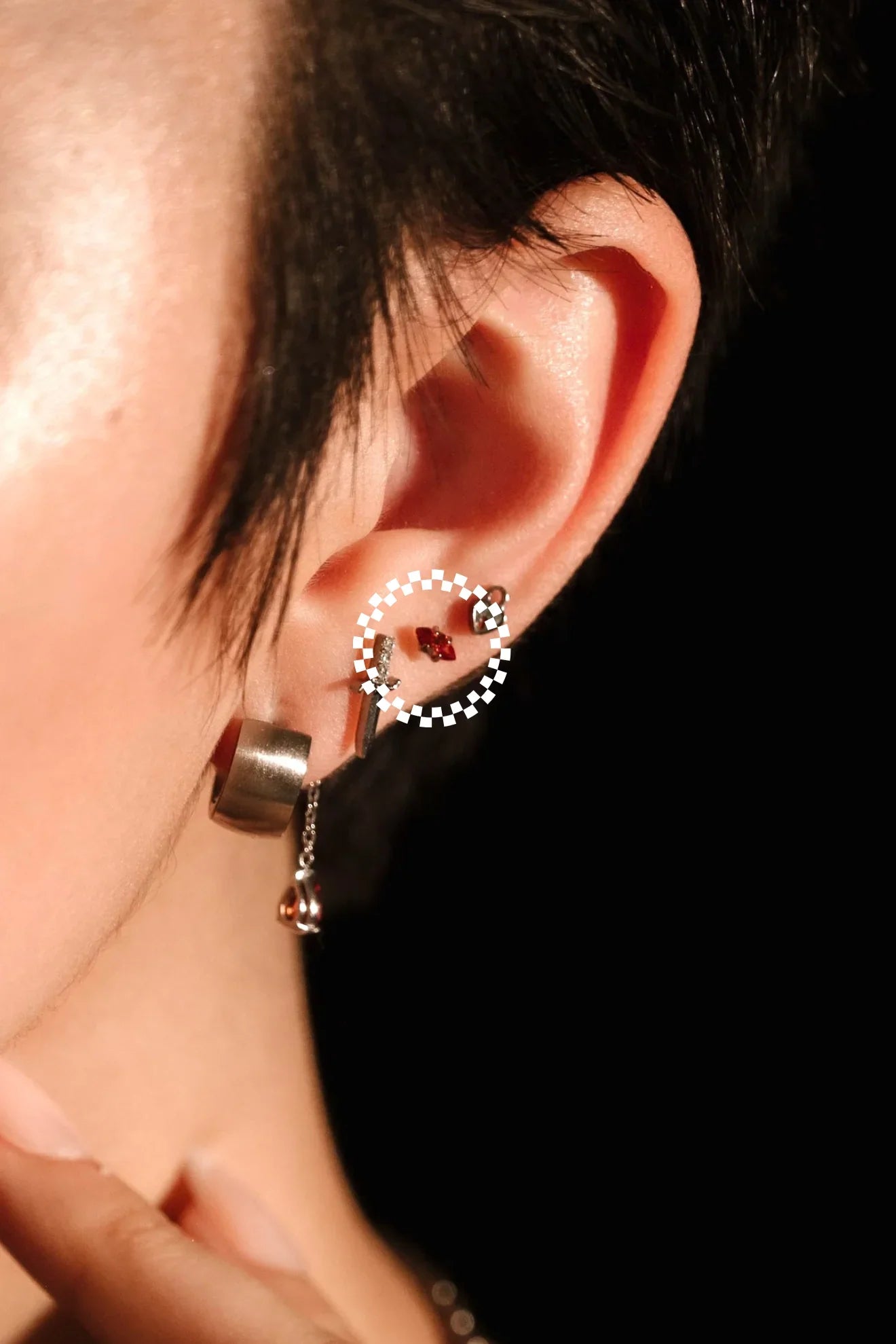 Close-up of an ear wearing a hoop earring with a dark background