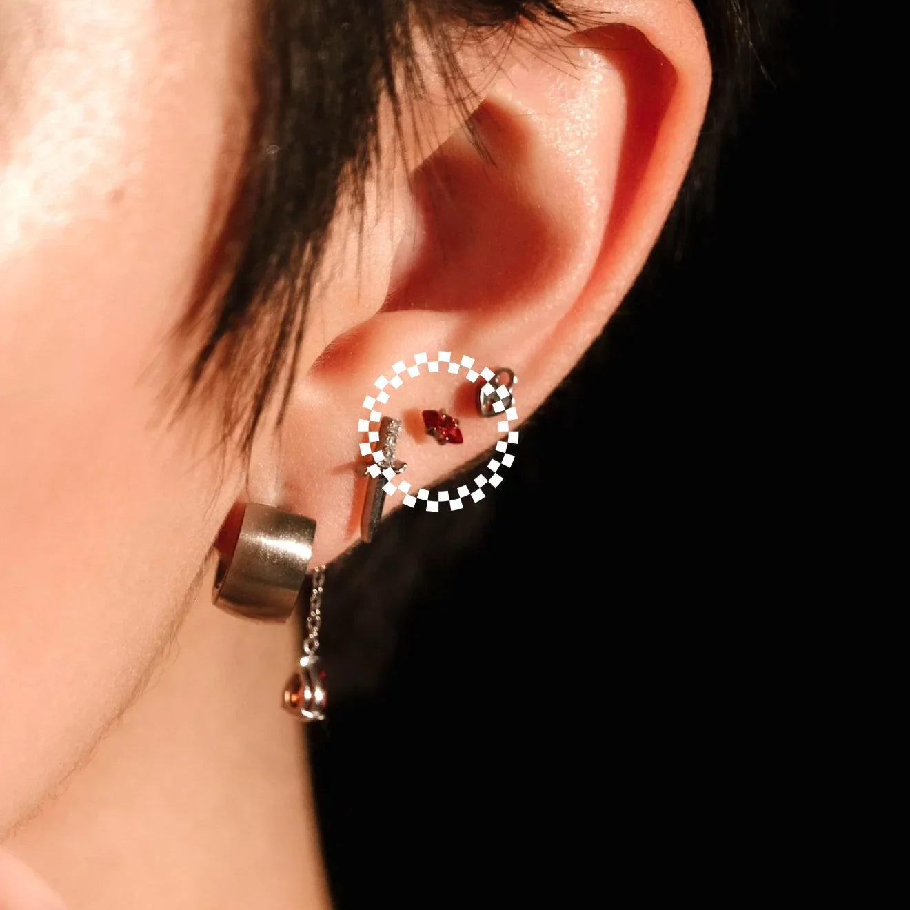 Close-up of an ear wearing a hoop earring with a dark background