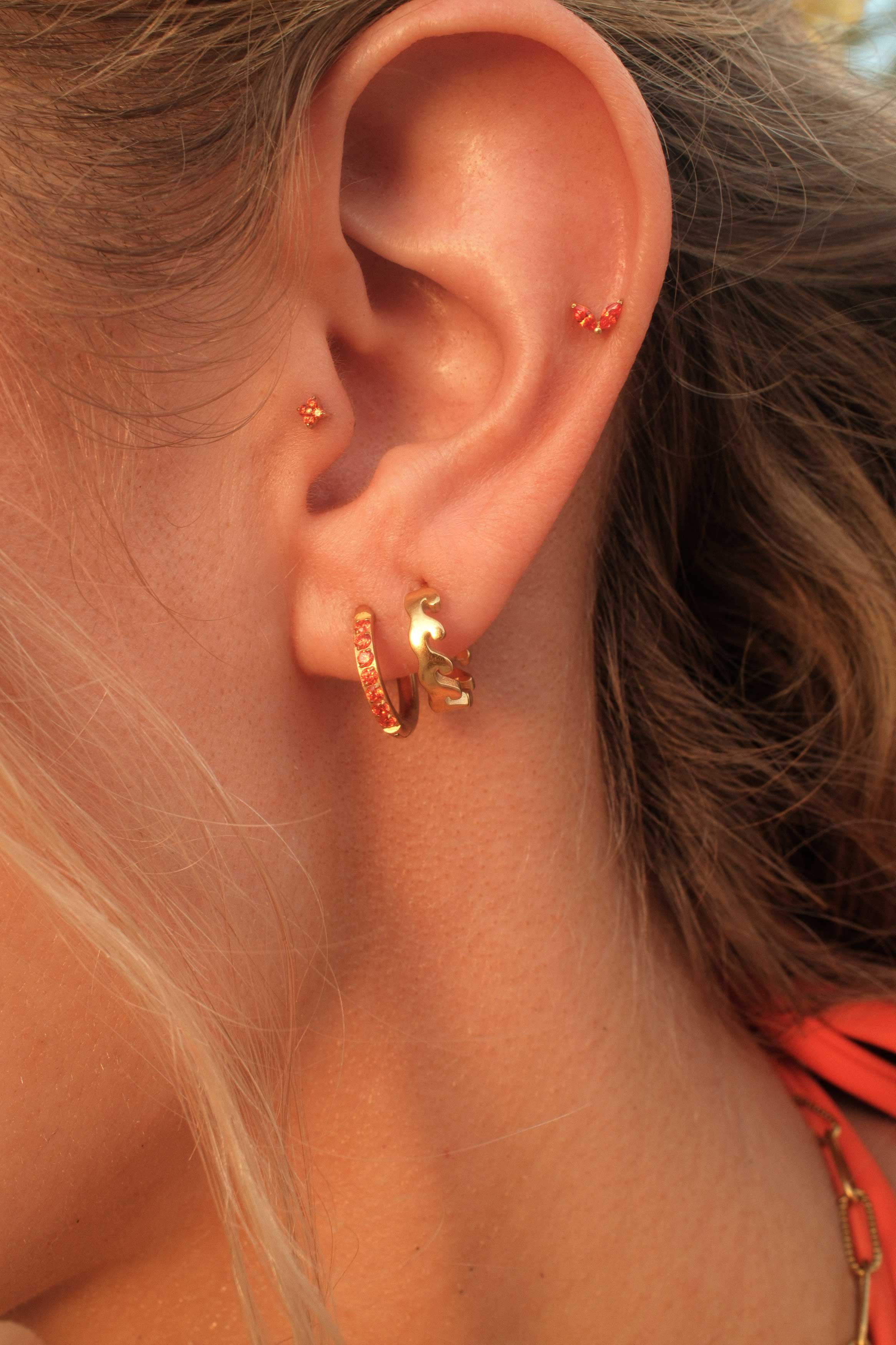 Close-up of an ear wearing gold hoop earrings with a blurred background