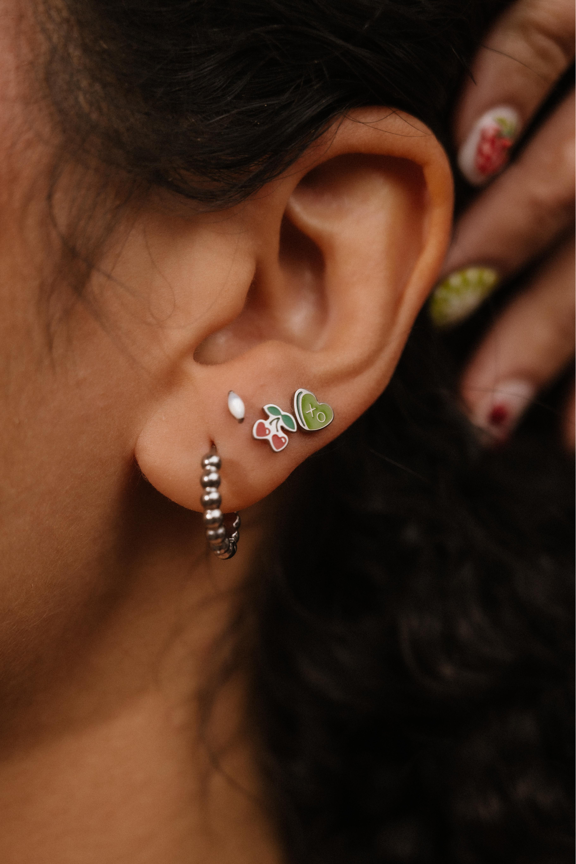 Close-up of an ear with multiple earrings, including a butterfly design.