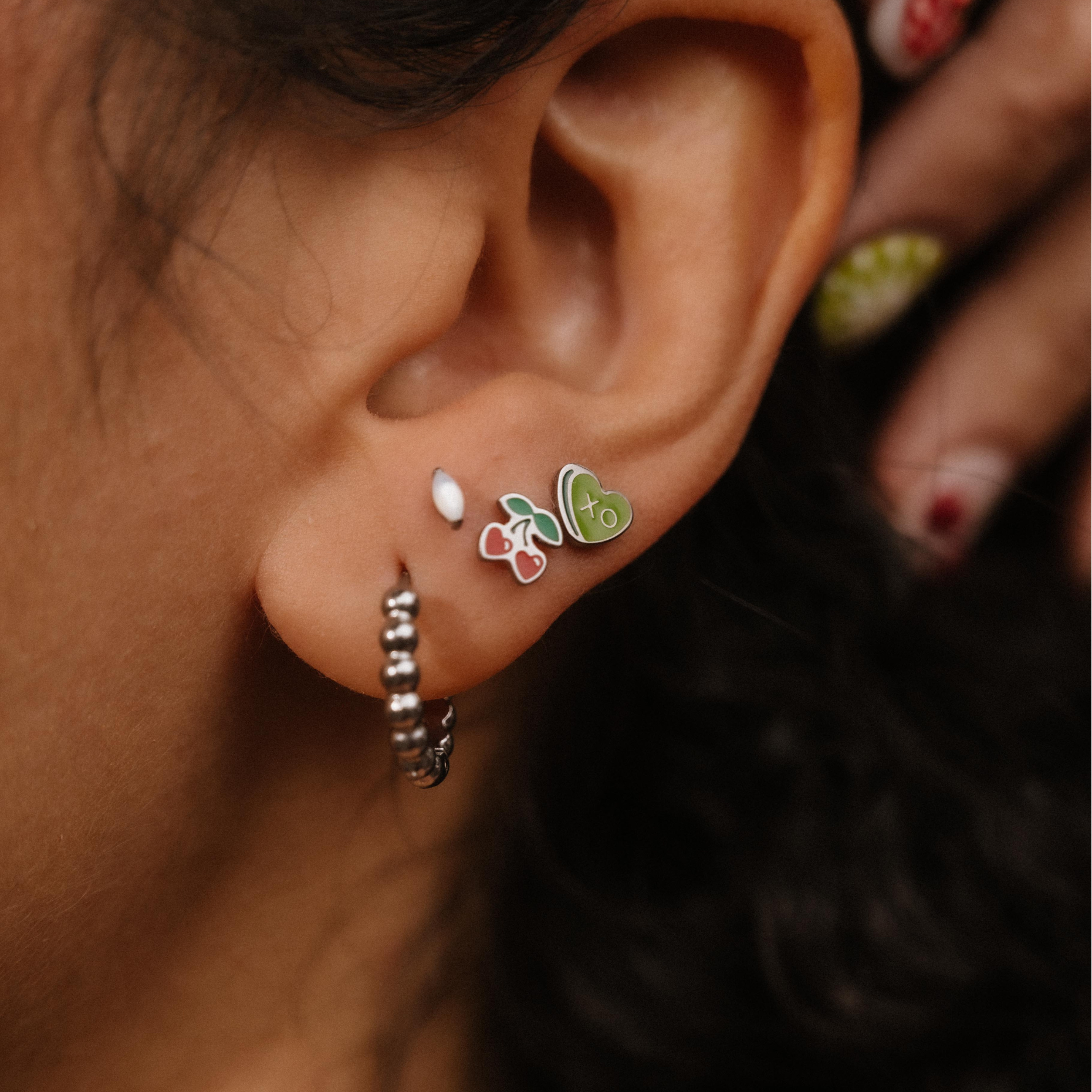 Close-up of an ear with multiple earrings, including a butterfly design.