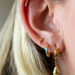 Close-up of an ear with gold earrings and a blurred background