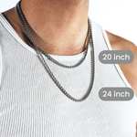 A close-up of a man wearing two silver-toned chain necklaces over a white ribbed tank top, with overlaid labels showing 20 inch and 24 inch lengths.