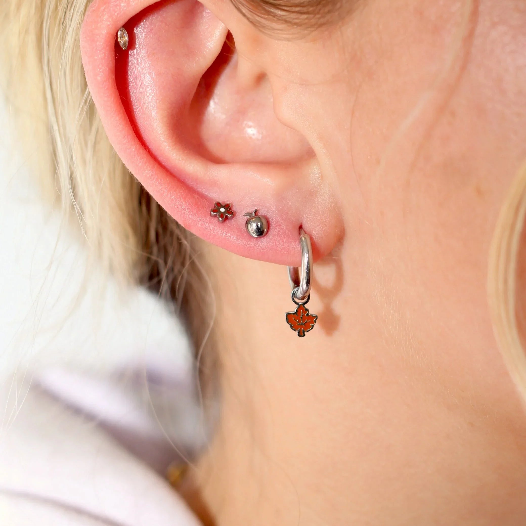 Close-up of a person's ear with multiple earrings.