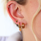 Close-up of an ear with gold hoop earrings on a blurred background
