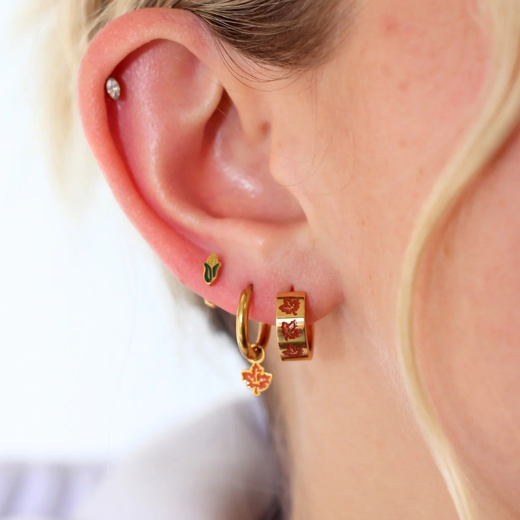 Close-up of an ear with gold hoop earrings on a blurred background