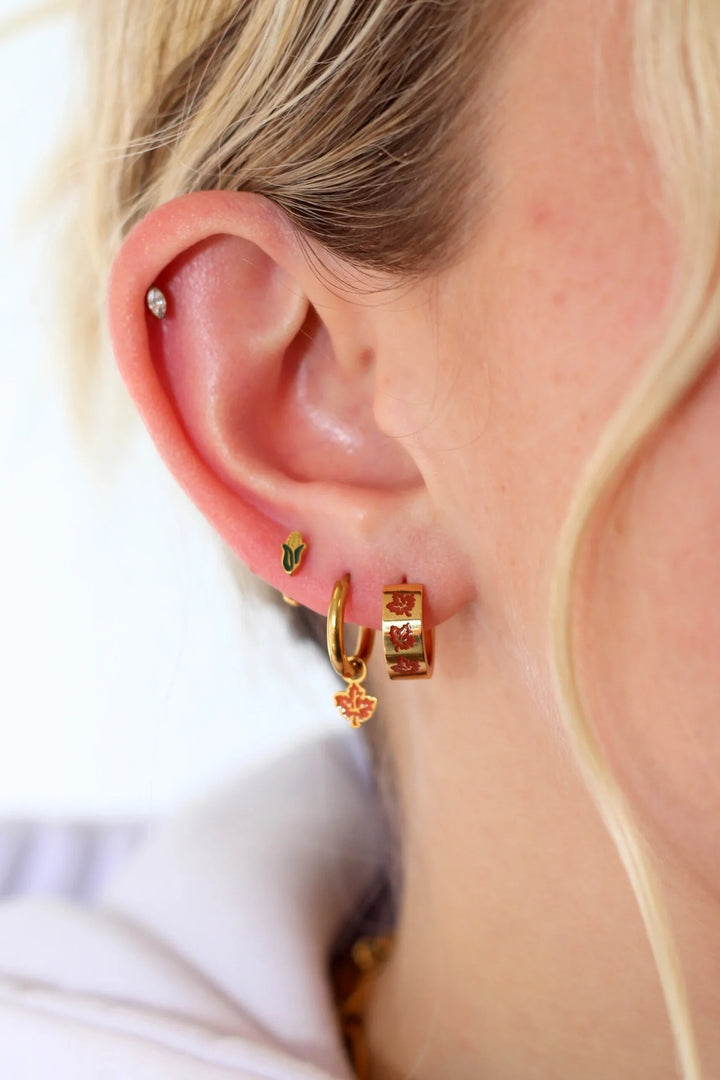 Close-up of an ear with gold hoop earrings on a blurred background
