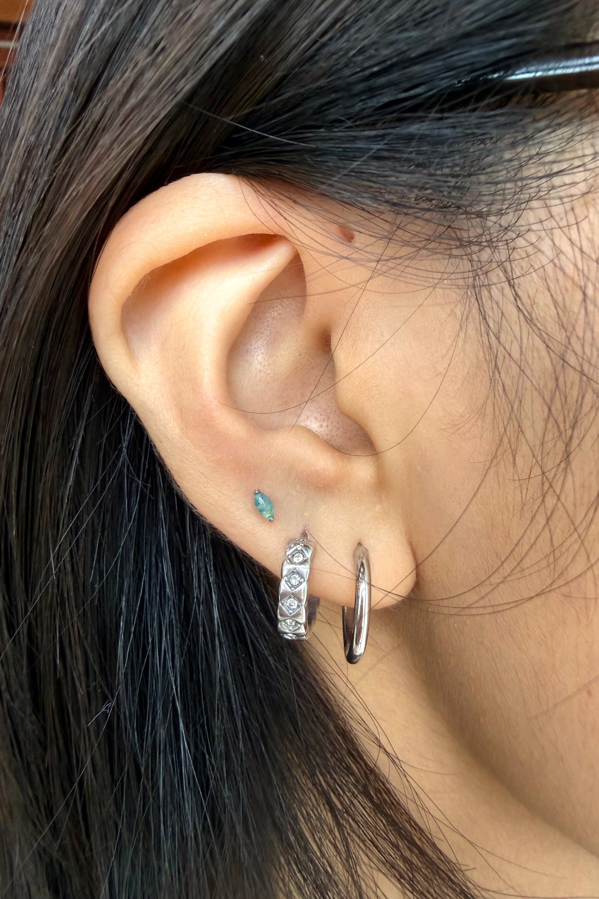 Close-up of an ear with multiple earrings against a blurred background
