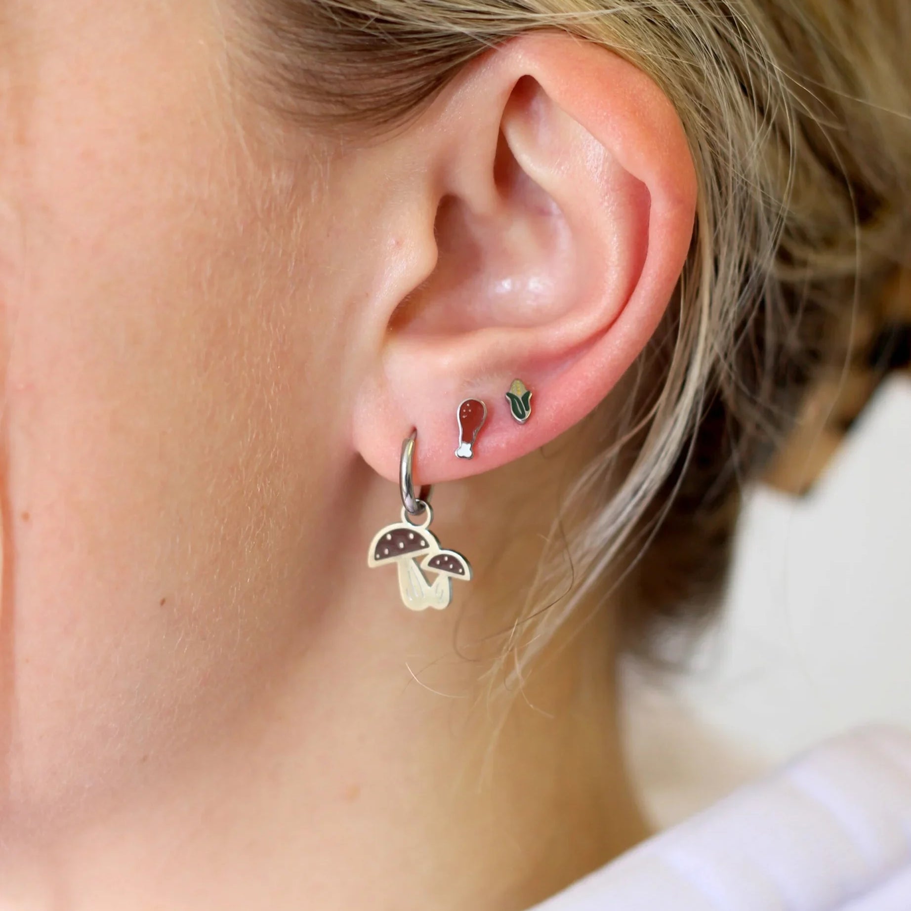 Close-up of a person's ear with multiple earrings.