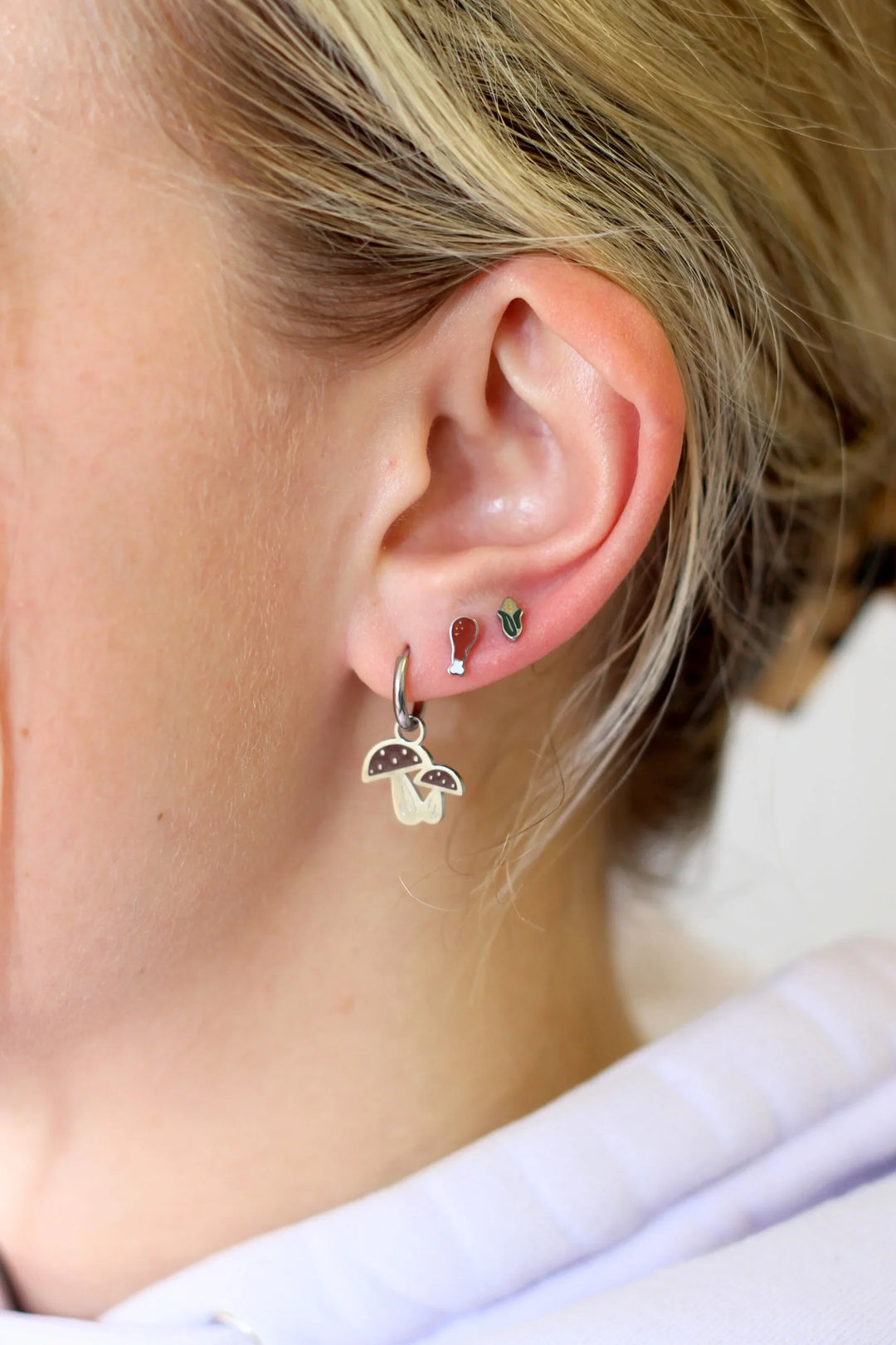 Close-up of a person's ear with multiple earrings.
