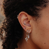 Close-up of an ear with multiple earrings against a blurred background