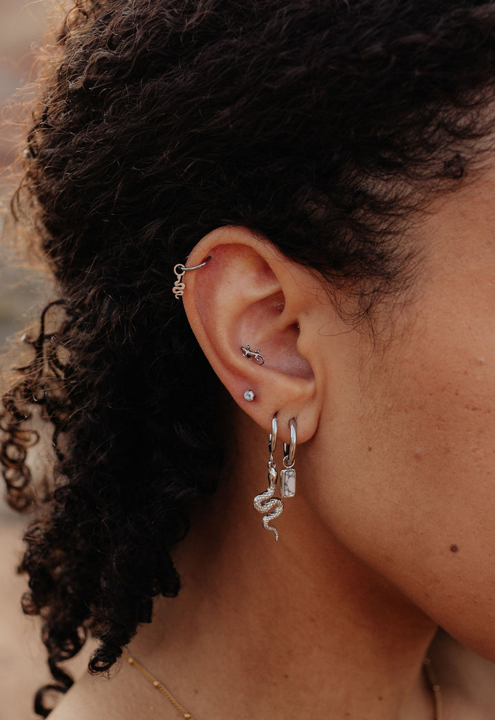 Close-up of an ear with multiple earrings against a blurred background