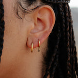 Close-up of an ear with gold hoop earrings and braided hair.