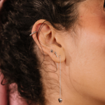 Close-up of an ear with multiple silver earrings against a blurred background