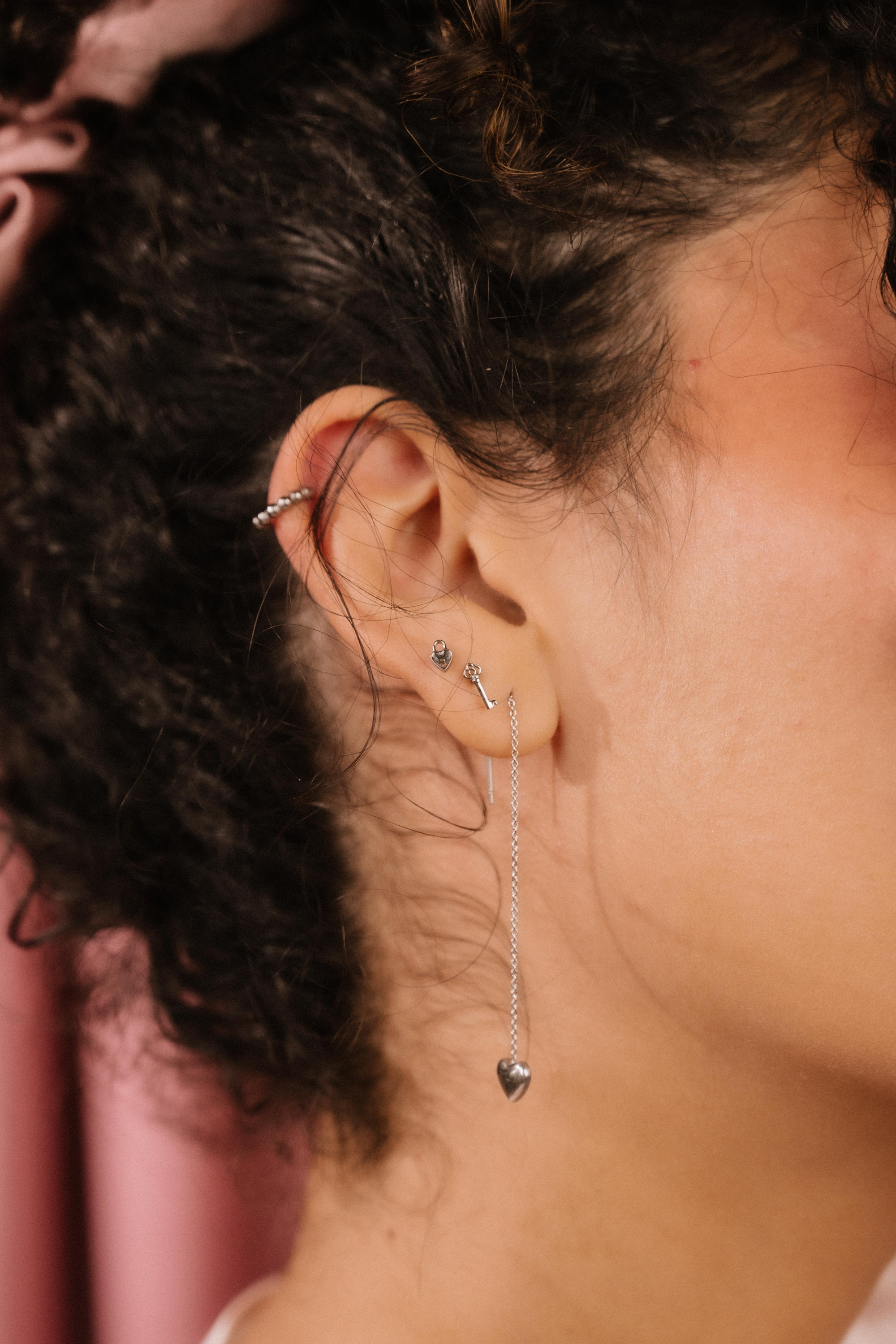 Close-up of an ear with multiple silver earrings against a blurred background