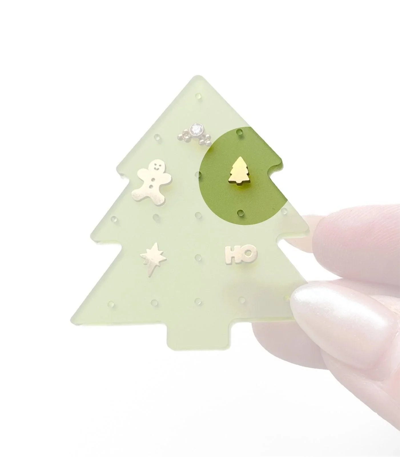 Christmas tree-shaped jewelry organizer with various small holiday-themed flat back studs, on a white background
