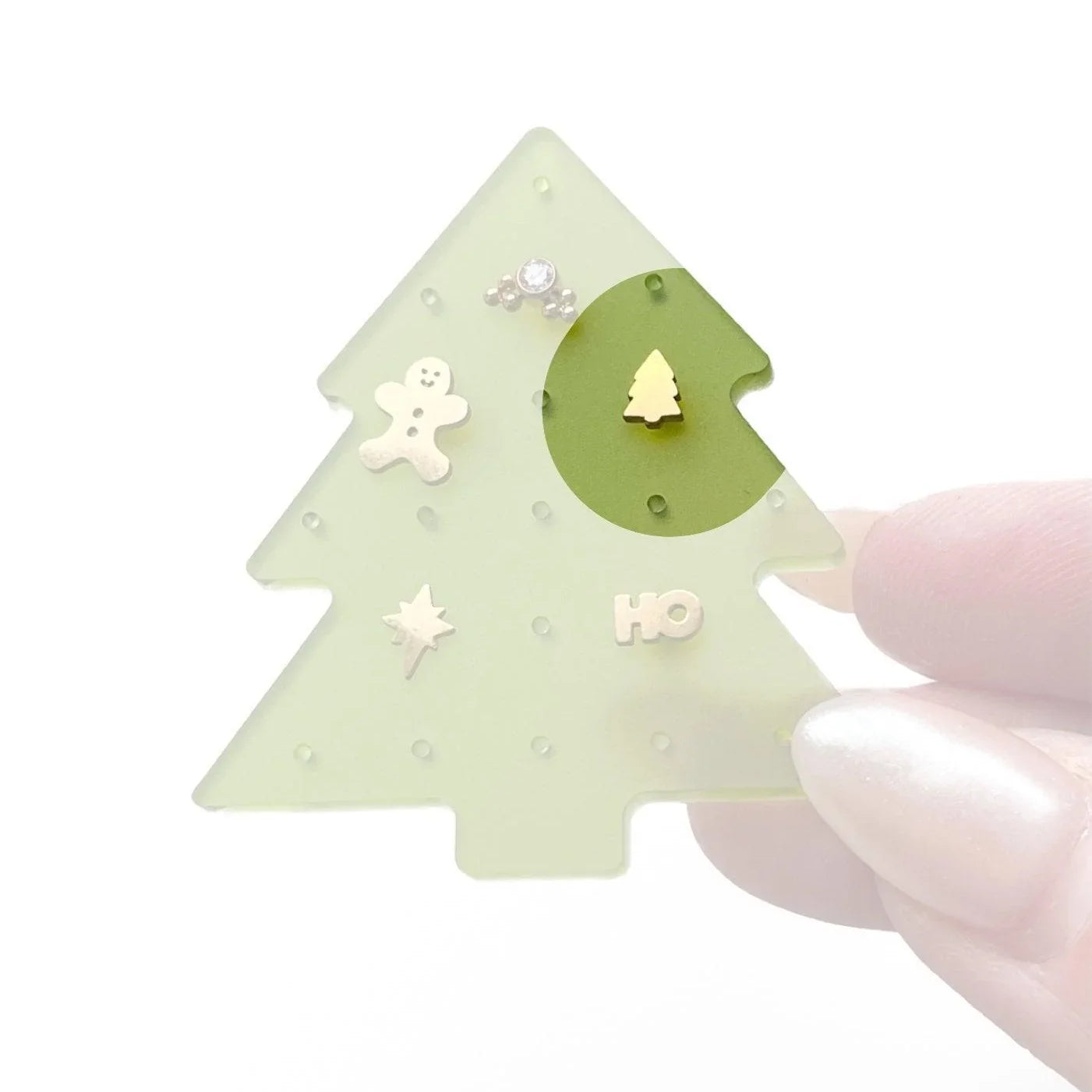 Christmas tree-shaped jewelry organizer with various small holiday-themed flat back studs, on a white background