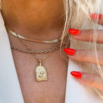 Close-up of a person wearing gold necklaces with a pendant, focusing on the jewelry.